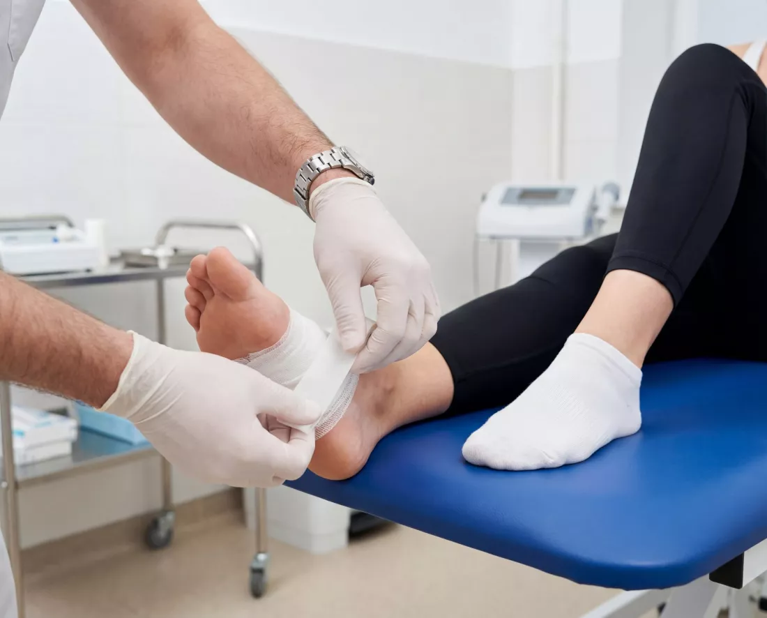 Doctor bandaging the foot of a patient in a clinic