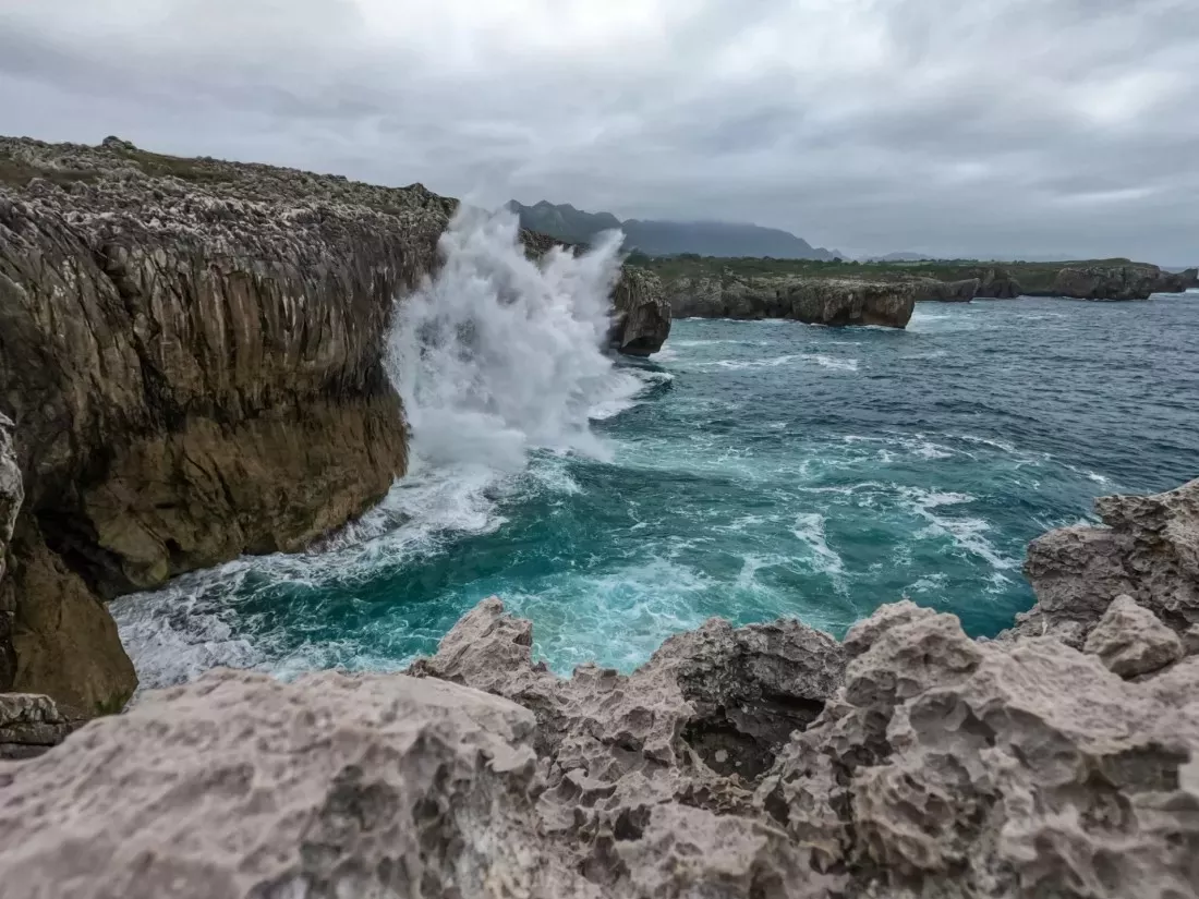 Wave crashing against a rocky cliff by the sea in Asturias